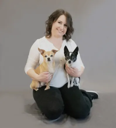 Alison sitting on the floor and holding 2 chihuahuas.