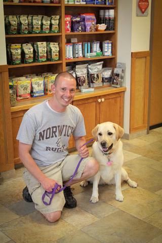 Client and dog posing in front of shelves full of pet supplies