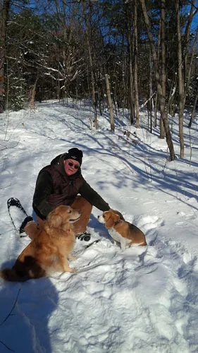 Two dogs in the snow with their owner