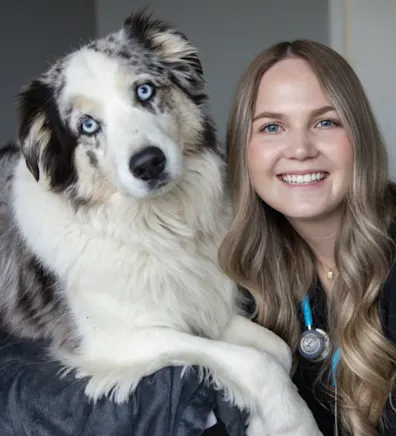 Makena smiling with a fluffy Australian dog with blue eyes