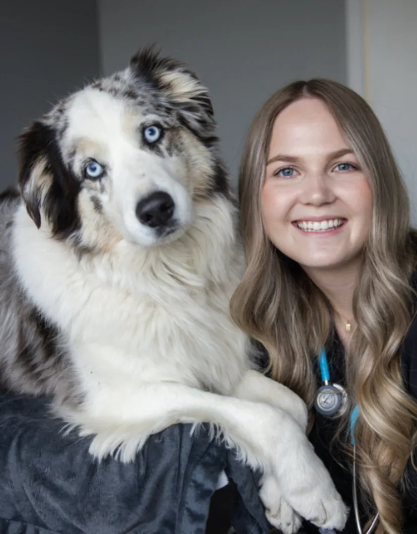 Makena smiling with a fluffy Australian dog with blue eyes