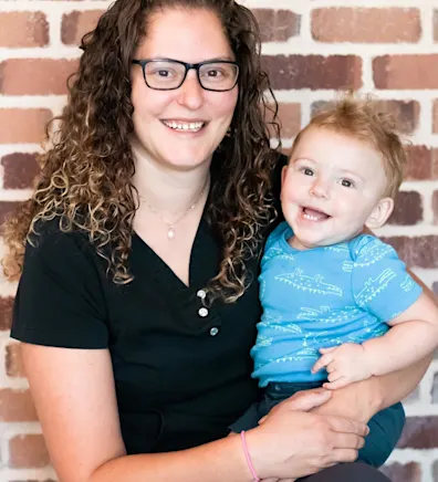 Nicole in front of a brick wall with her baby