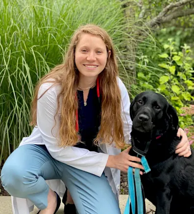 Dr. Tobi Navratil posing next to black dog Dr. Tobi Navratil posing next to black dog