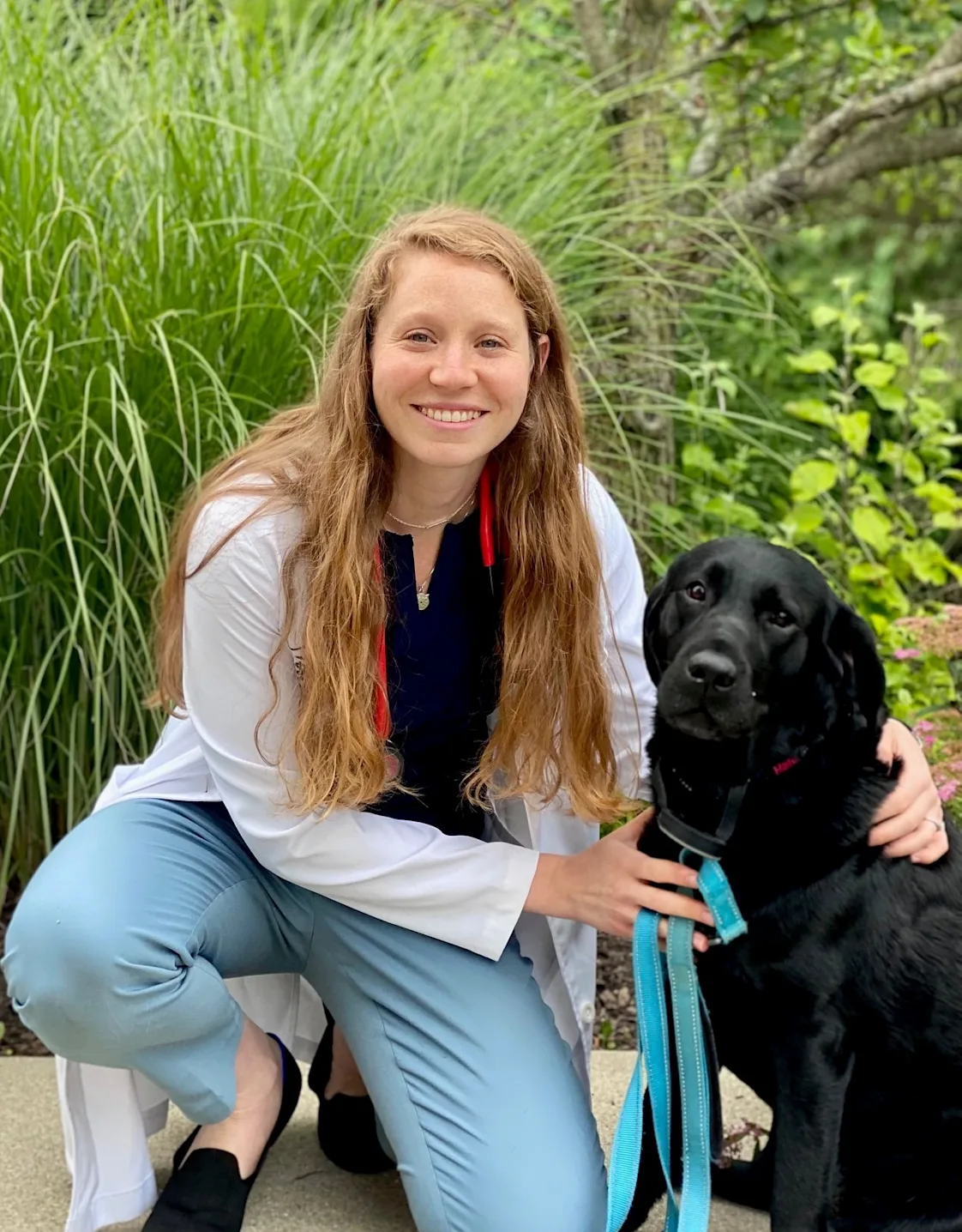 Dr. Tobi Navratil posing next to black dog Dr. Tobi Navratil posing next to black dog