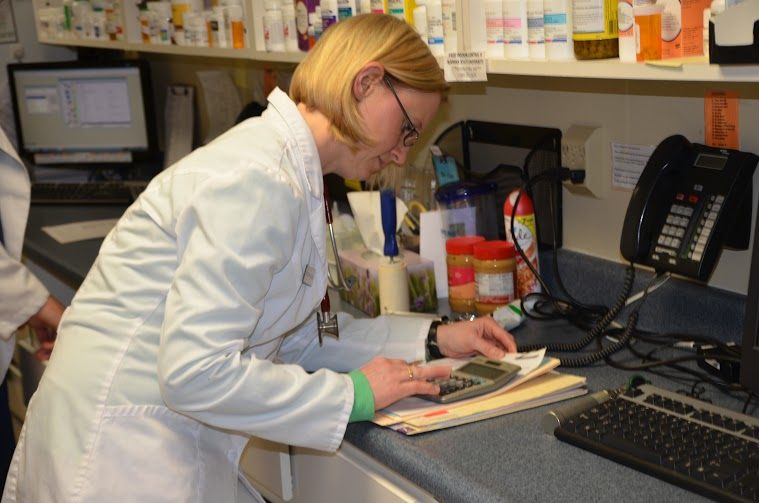 Veterinarian looking at calculator at desk