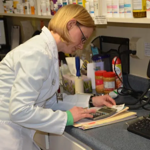 Veterinarian looking at calculator at desk