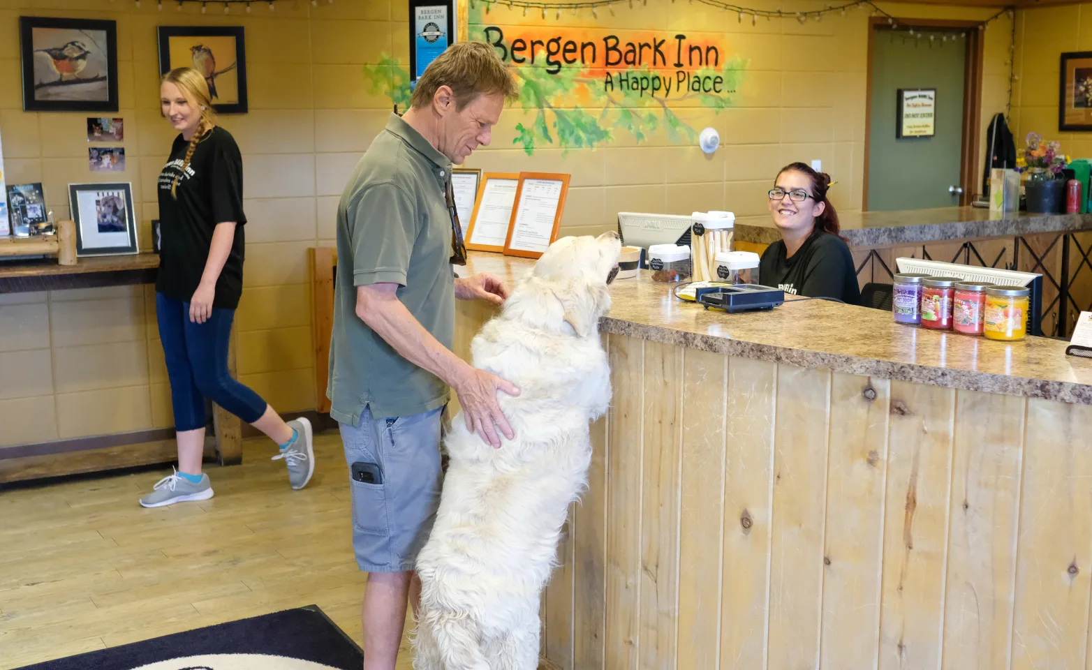 Front desk with customer and their dog next to him with paws on counter