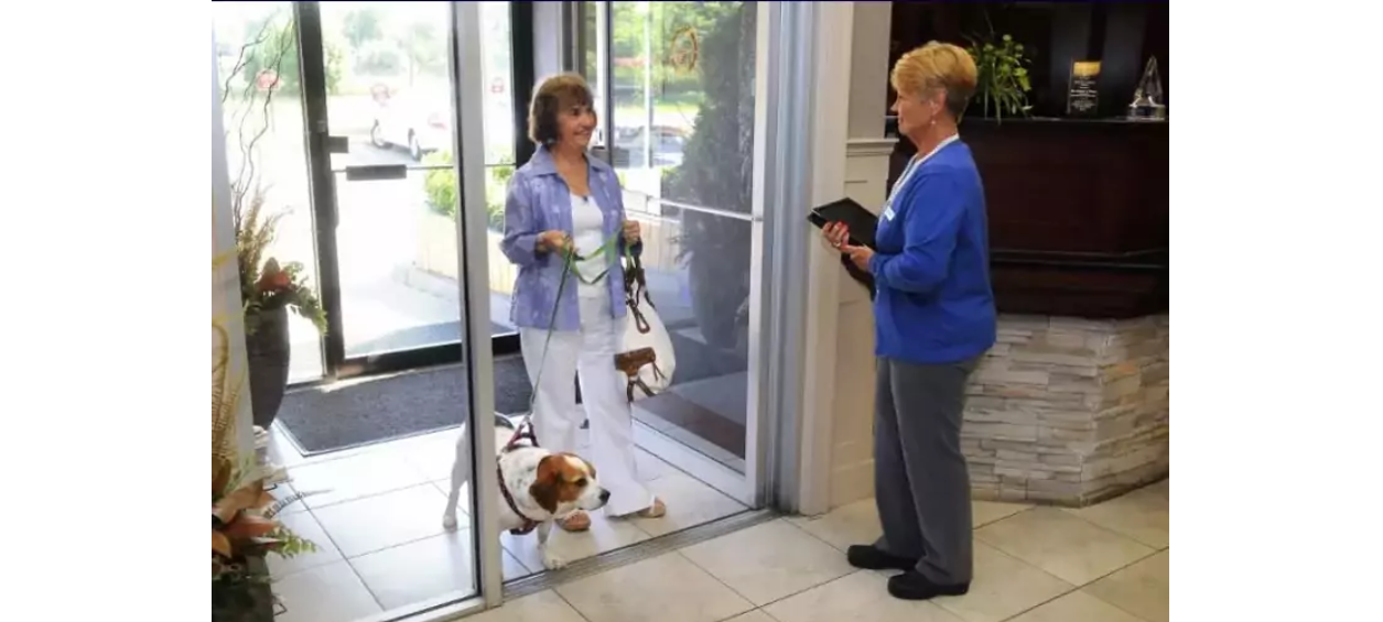 Client with her dog being greeted at the front entrance by a staff member.