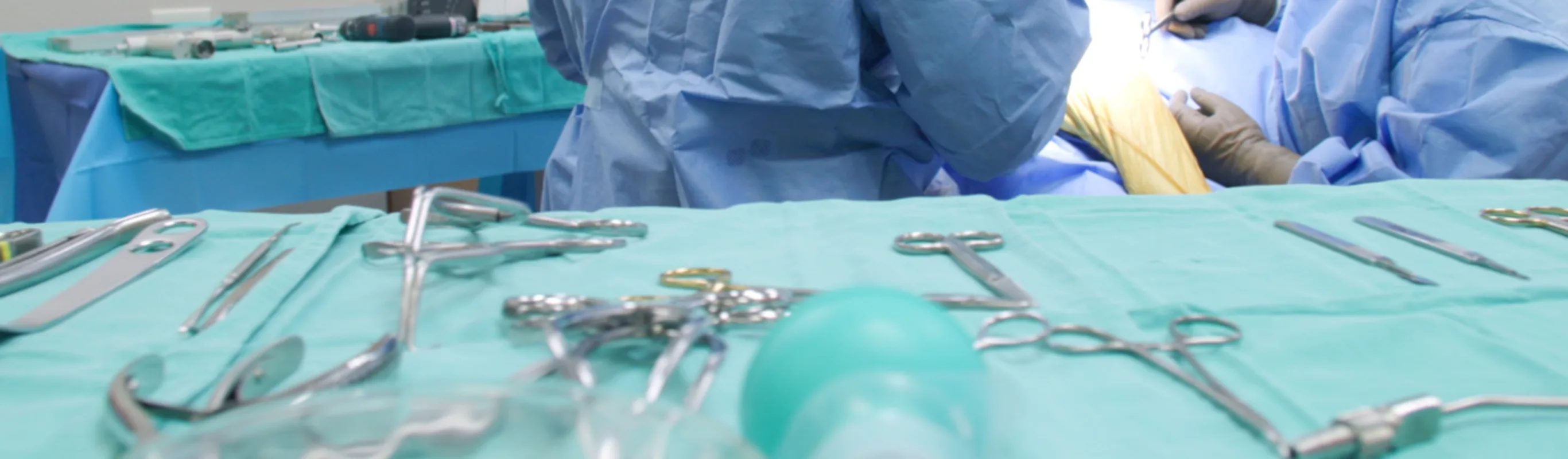 Surgical tools laid out on a table with a green plastic cloth