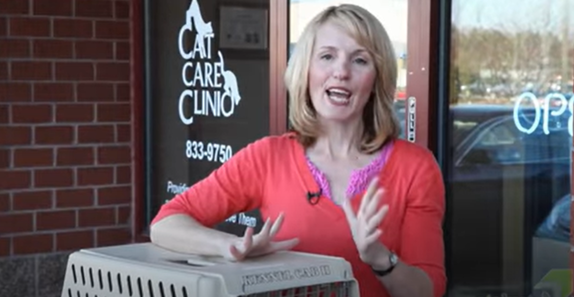 Woman in red shirt standing with a cat carrier