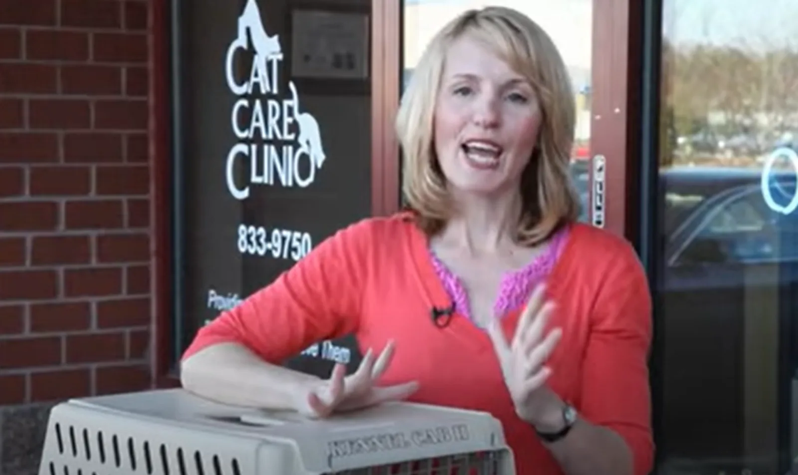 Woman in red shirt standing with a cat carrier