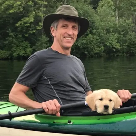 Dr. Dave Heaton posing in a kayak with a small puppy