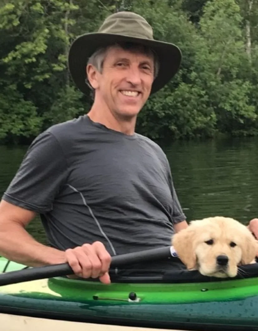 Dr. Dave Heaton posing in a kayak with a small puppy