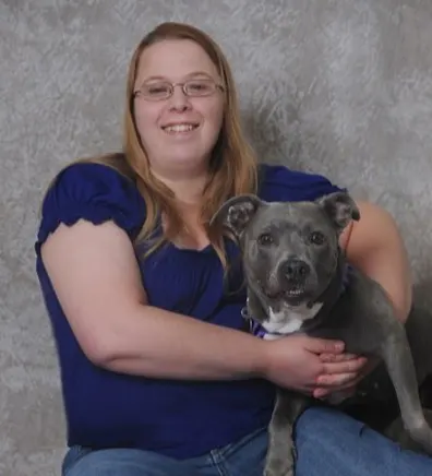 Alicia Carson's staff photo from Jefferson Road Animal Hospital where she is posing with a grey pitbull