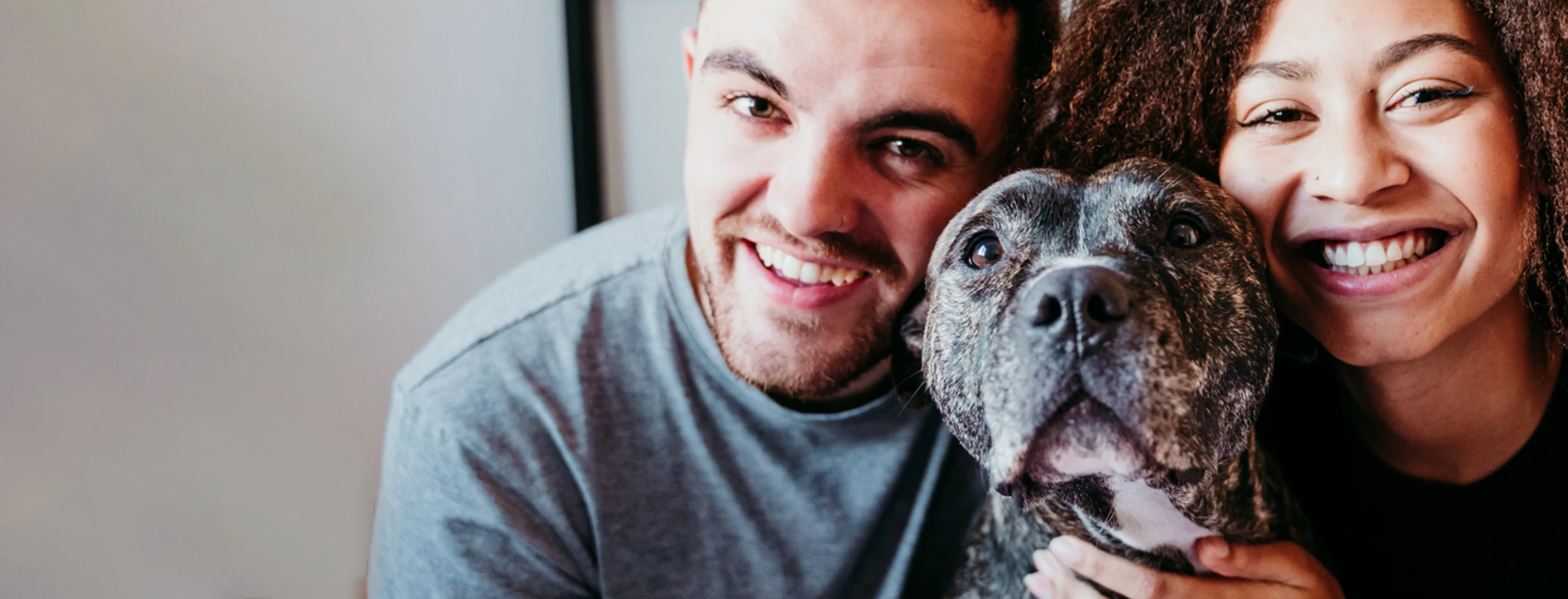 Two people smiling with their dog between them Two people smiling with their dog between them