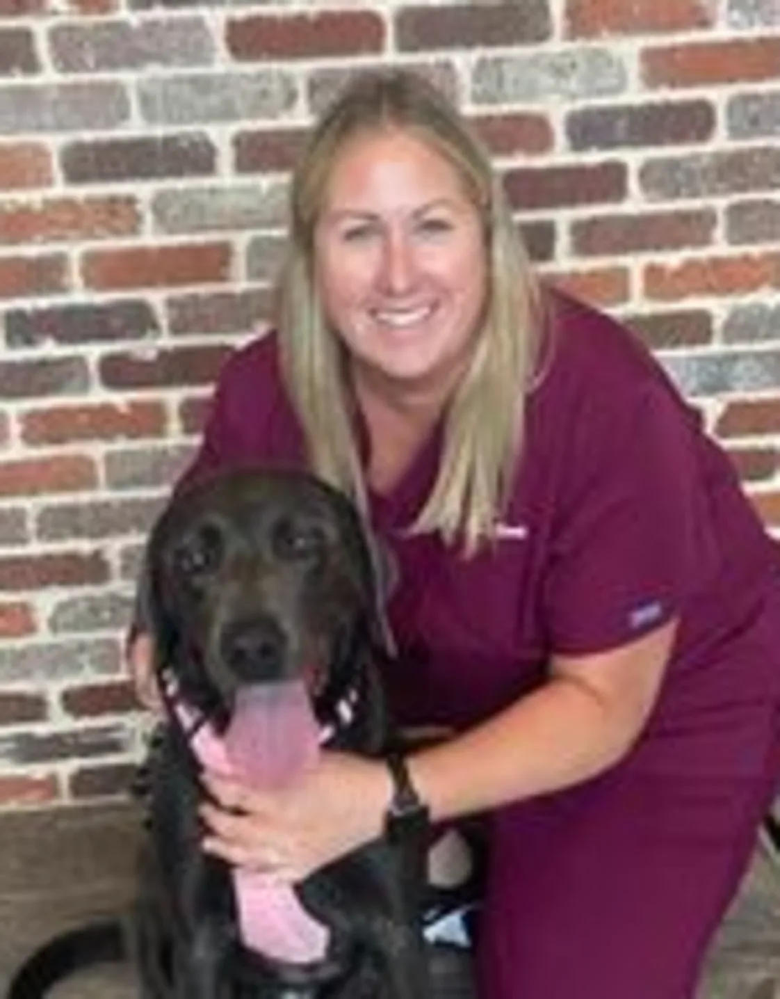 Tanya Burgess kneeling down next to a black dog Tanya Burgess kneeling down next to a black dog