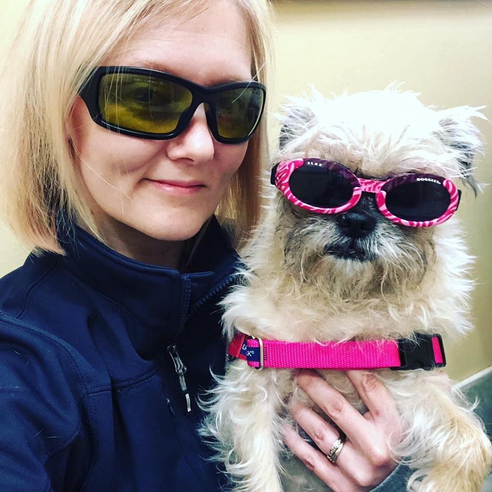 Staff member holding a dog with pink glasses