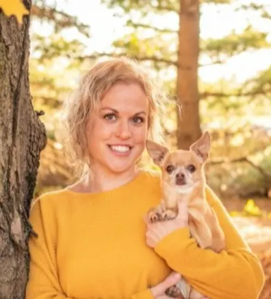 Ashley posing next to a tree holding a small dog Ashley posing next to a tree holding a small dog