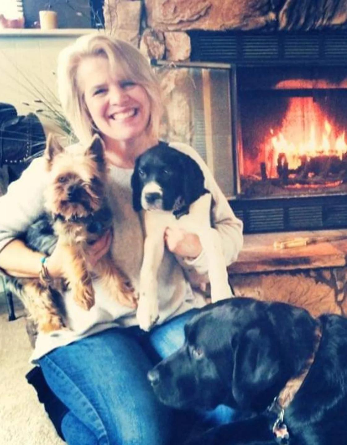 Cristi sitting in front of a fire place with her 3 dogs Cristi sitting in front of a fire place with her 3 dogs