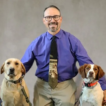 Dr. Bradley Coolman kneeling down next to two dogs