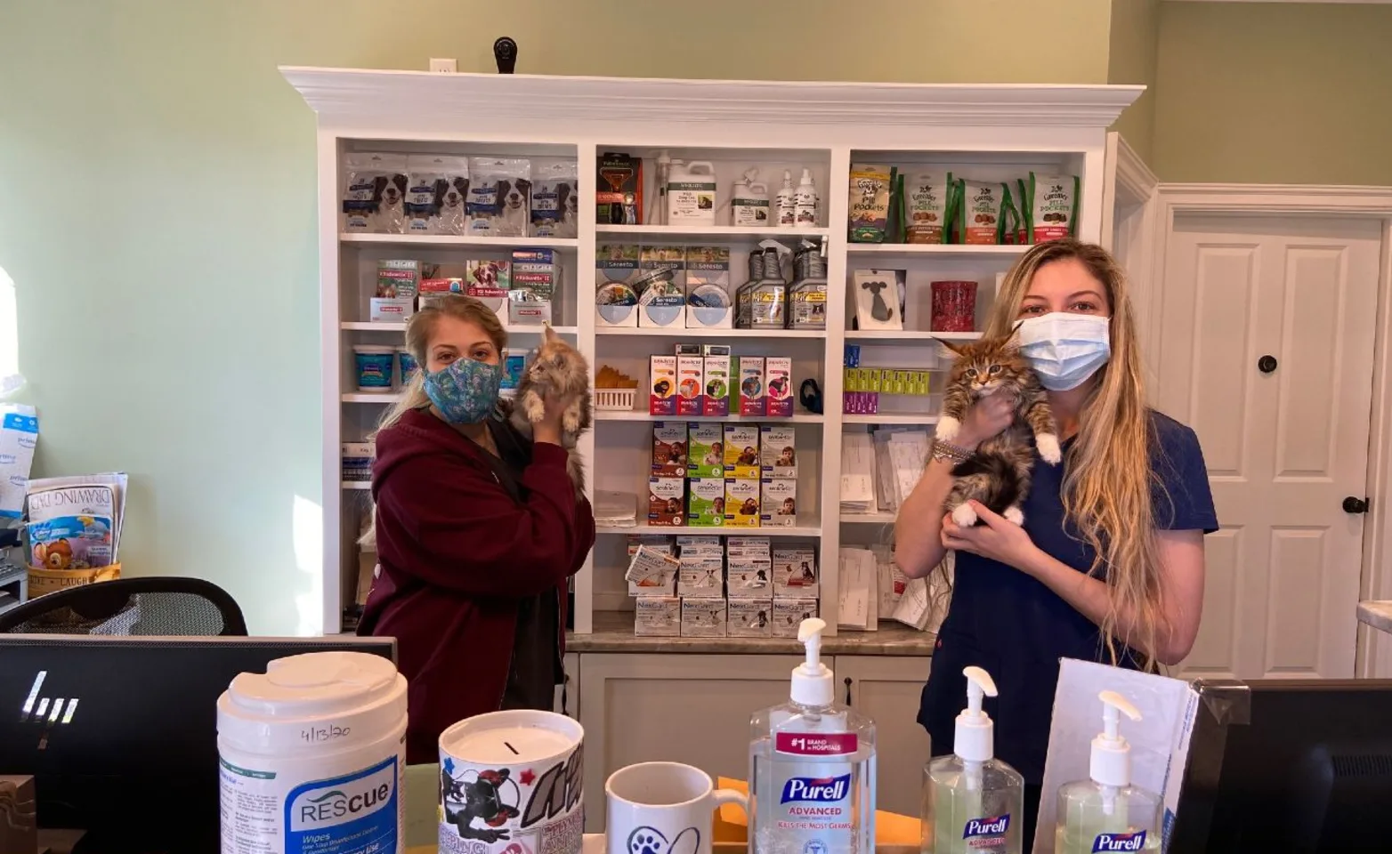 Staff at the reception desk with shelving with pharmacy medication behind them