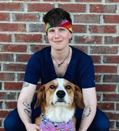 Cassie holding onto a beagle and smiling in a grassy field Cassie holding onto a beagle and smiling in a grassy field