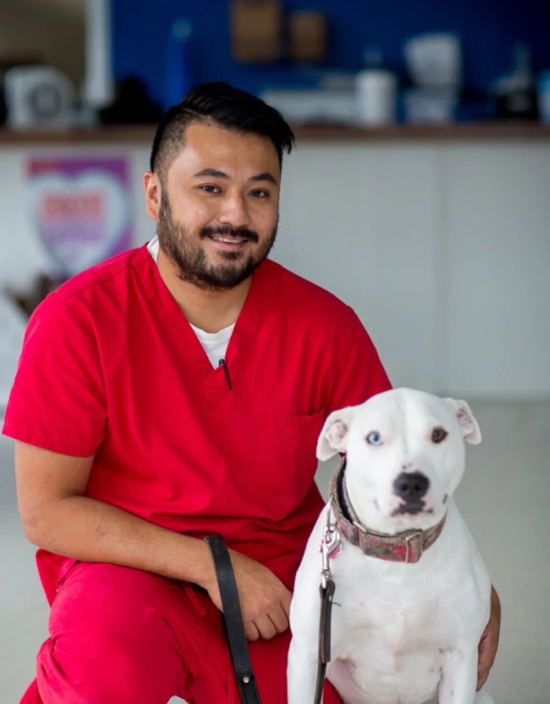 Arnold in red scrubs with a white dog from Tacoma Animal Hospital Arnold in red scrubs with a white dog from Tacoma Animal Hospital