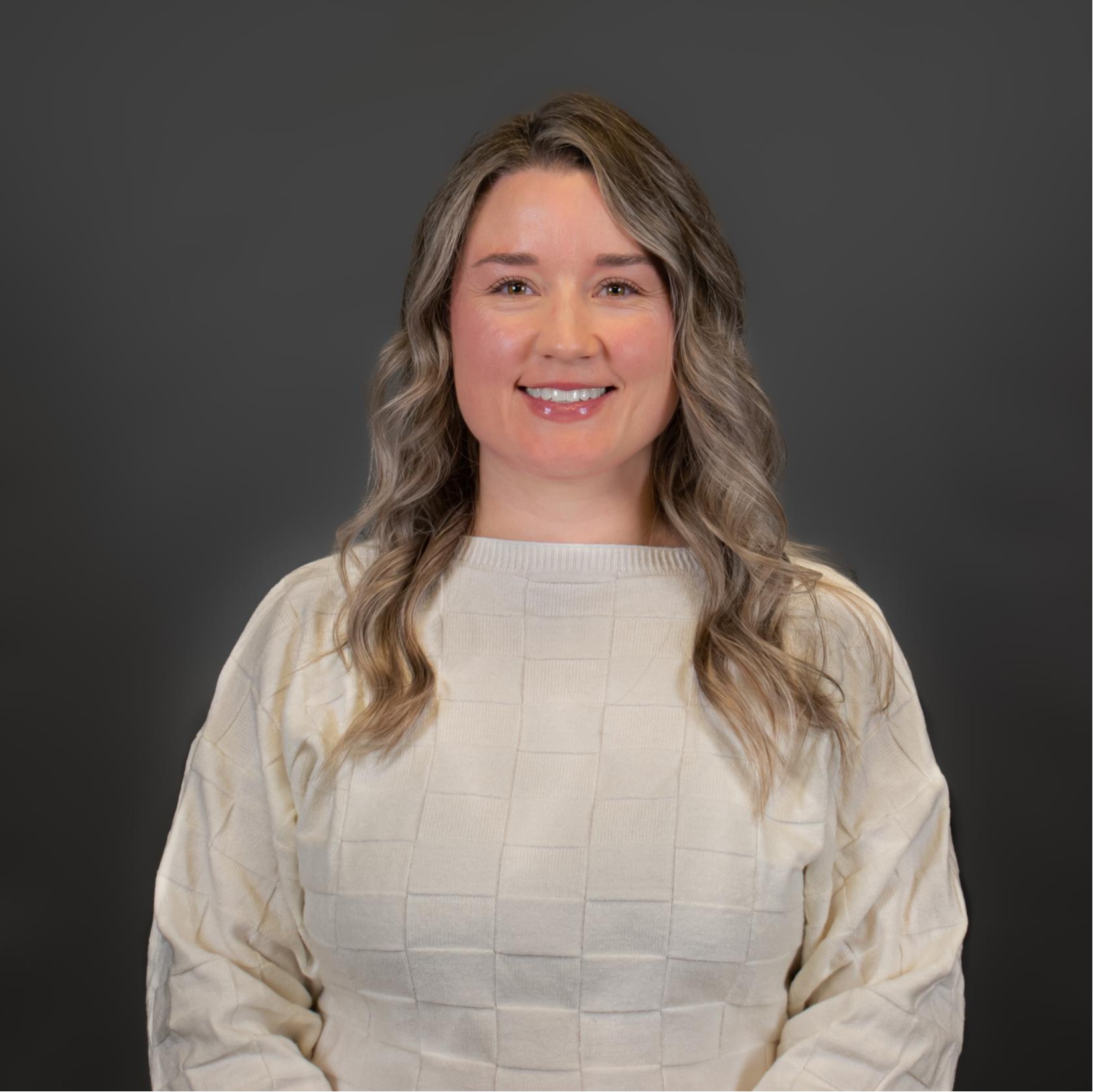 Kathryn McCutcheon holding two black and brown dogs, with the one one her left wearing a blue bandana and the one on the right wearing a pink flower on its neck.