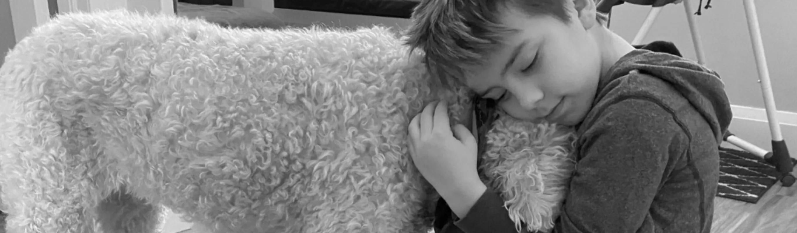 Black and white photo of a child hugging a dog