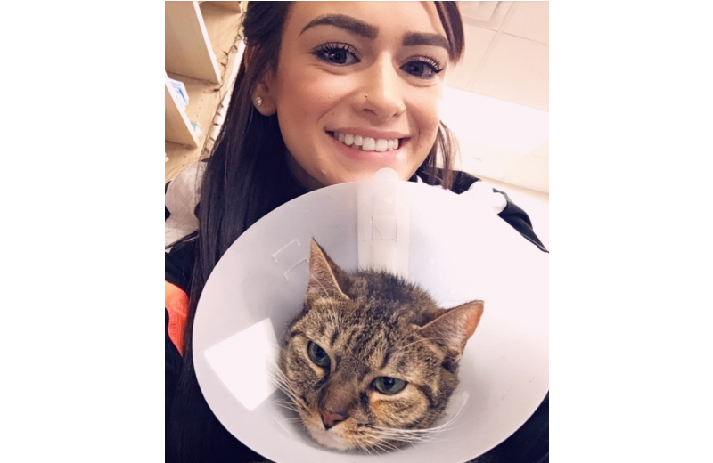 Woman Smiling Holding a Cat with a Cone