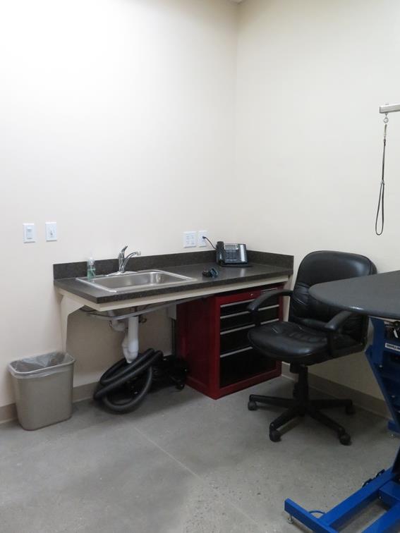 A sink area inside a desk, a chair and examination table. 