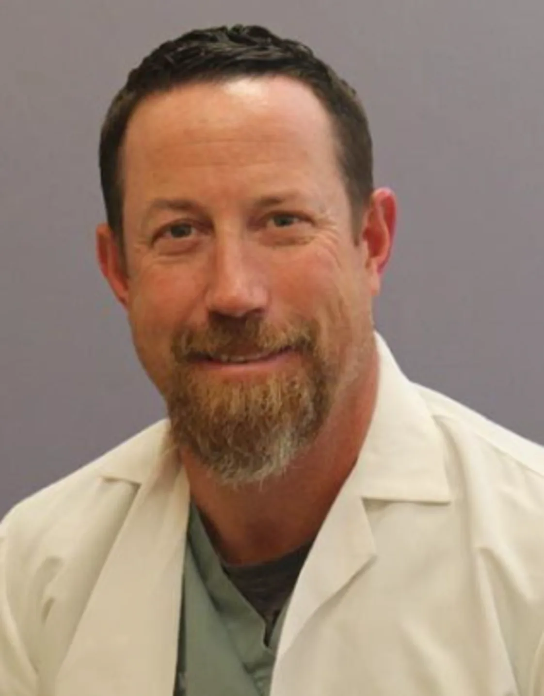 Carl F. Agnello smiling in front of a grey wall wearing a white lab coat Carl F. Agnello smiling in front of a grey wall wearing a white lab coat