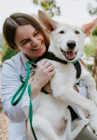 Staff smiling with White dog smiling at North Creek Pet Hospital