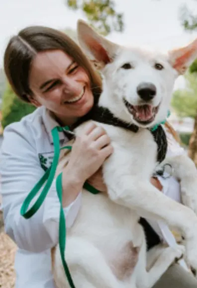 Staff smiling with White dog smiling at North Creek Pet Hospital Staff smiling with White dog smiling at North Creek Pet Hospital