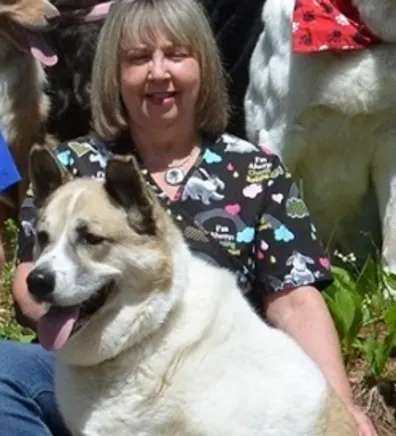 Terrie smiling, sitting out side with a large fluffy white and brown dog