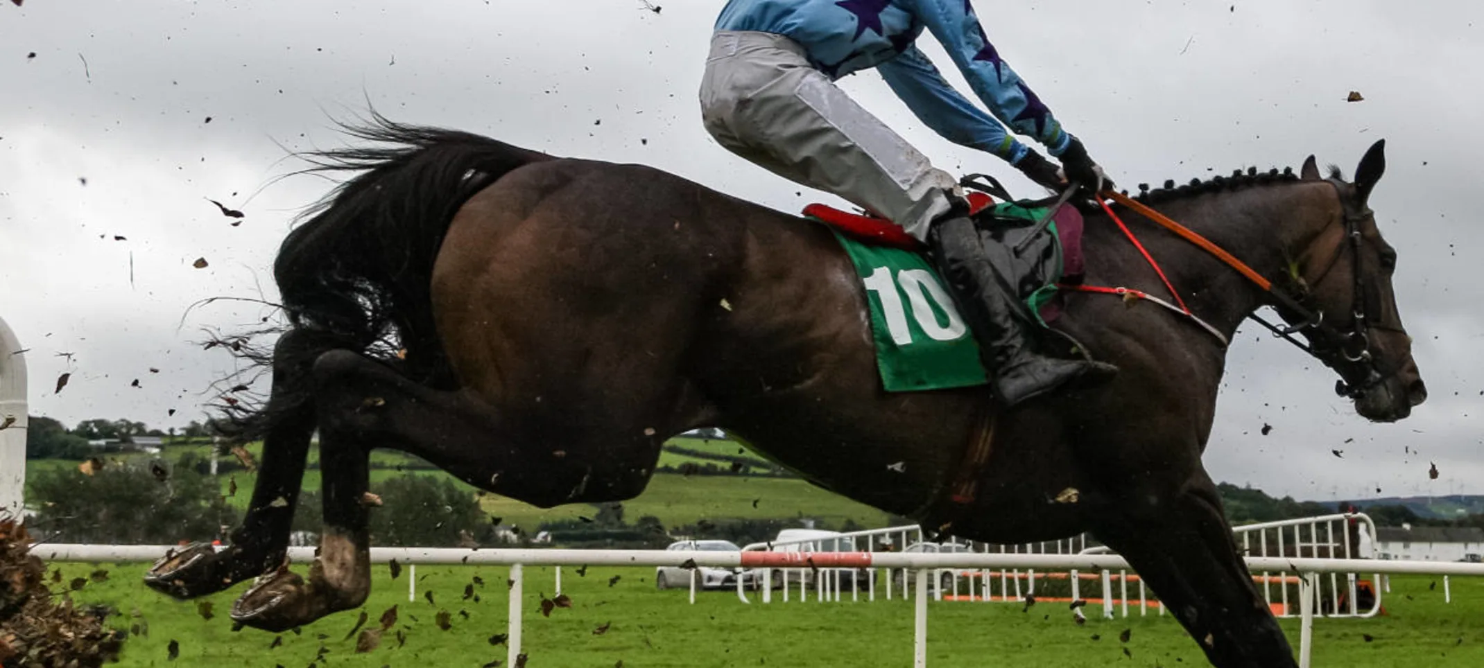 Race horses and jockeys jumping over a hurdle