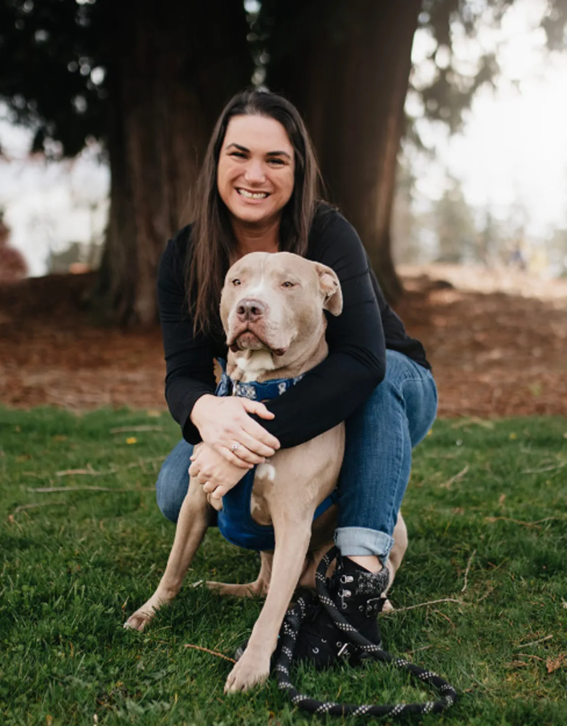 Patricia OJala kneeling and wrapping her arms around a Pitbull dog Patricia OJala kneeling and wrapping her arms around a Pitbull dog