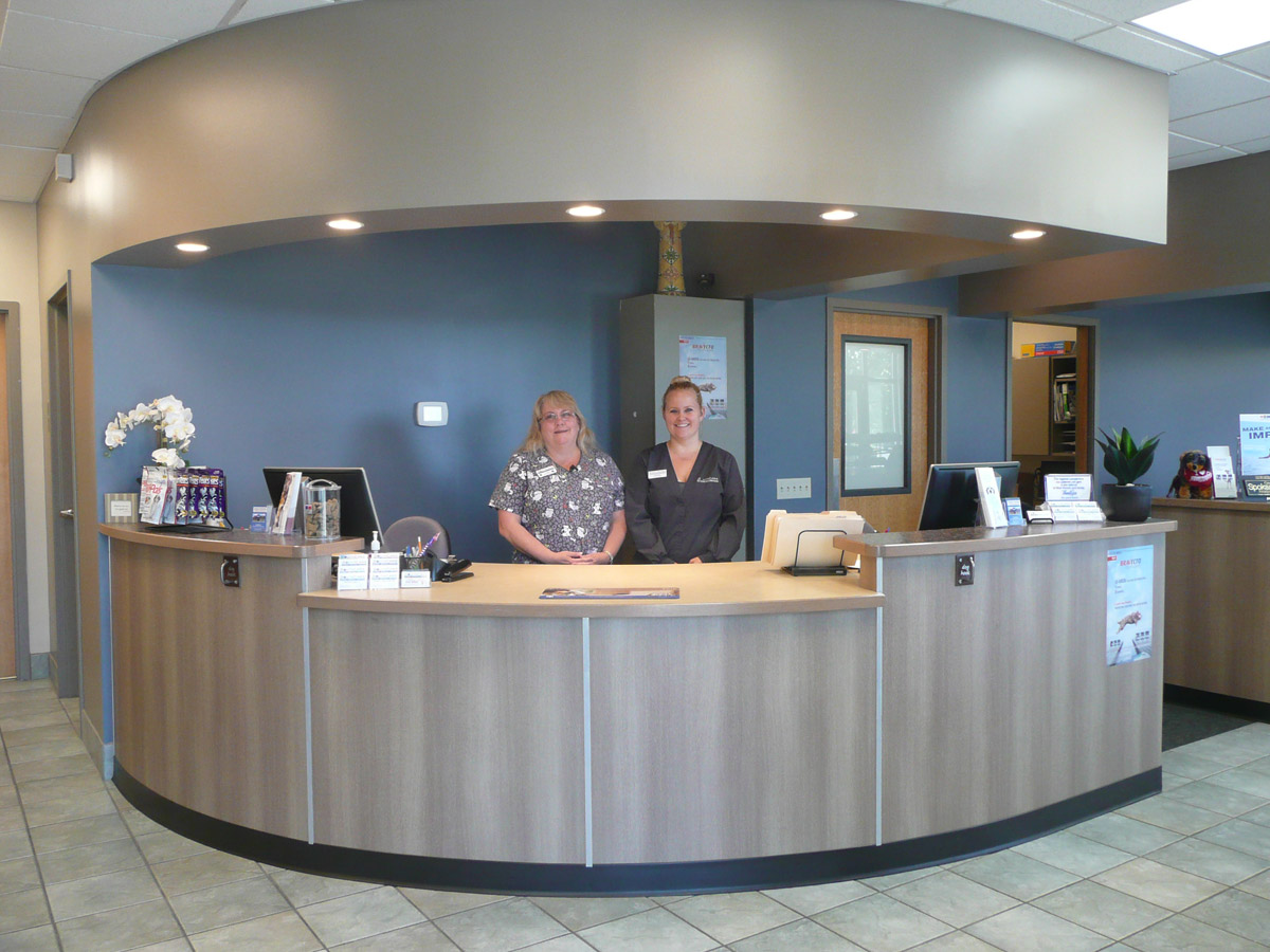 two staff members stand behind the front desk of SouthCare Animal Medical Center