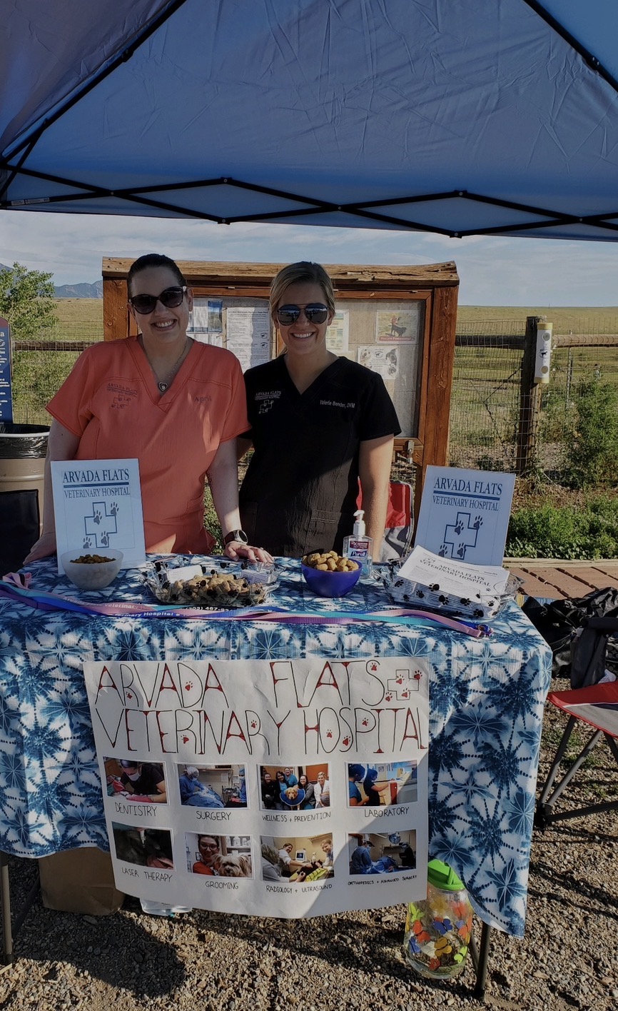 Two team members standing behind the Arvada flats veterinary hospital event table
