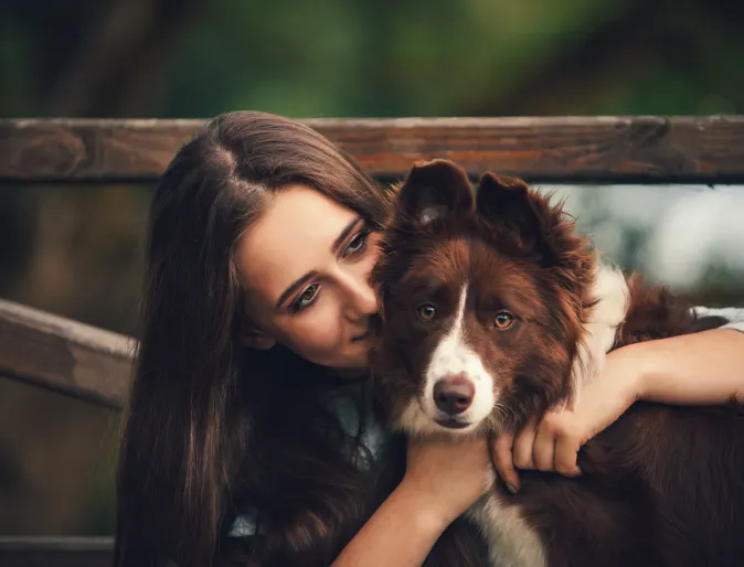 Woman hugging dog in front of gate