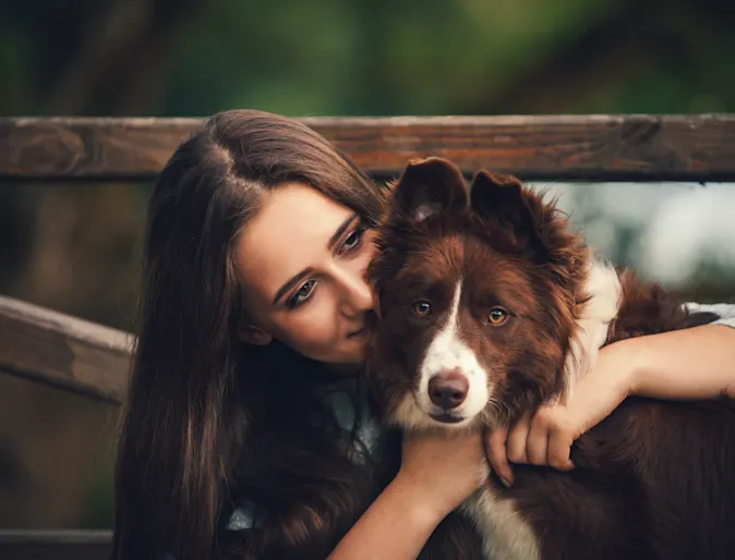 Woman hugging dog in front of gate Woman hugging dog in front of gate