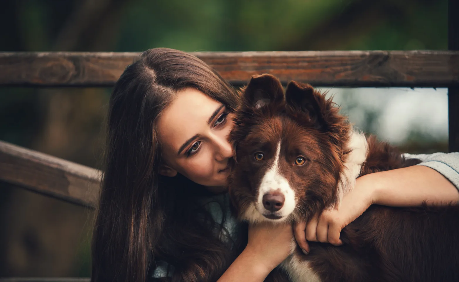Woman hugging dog in front of gate