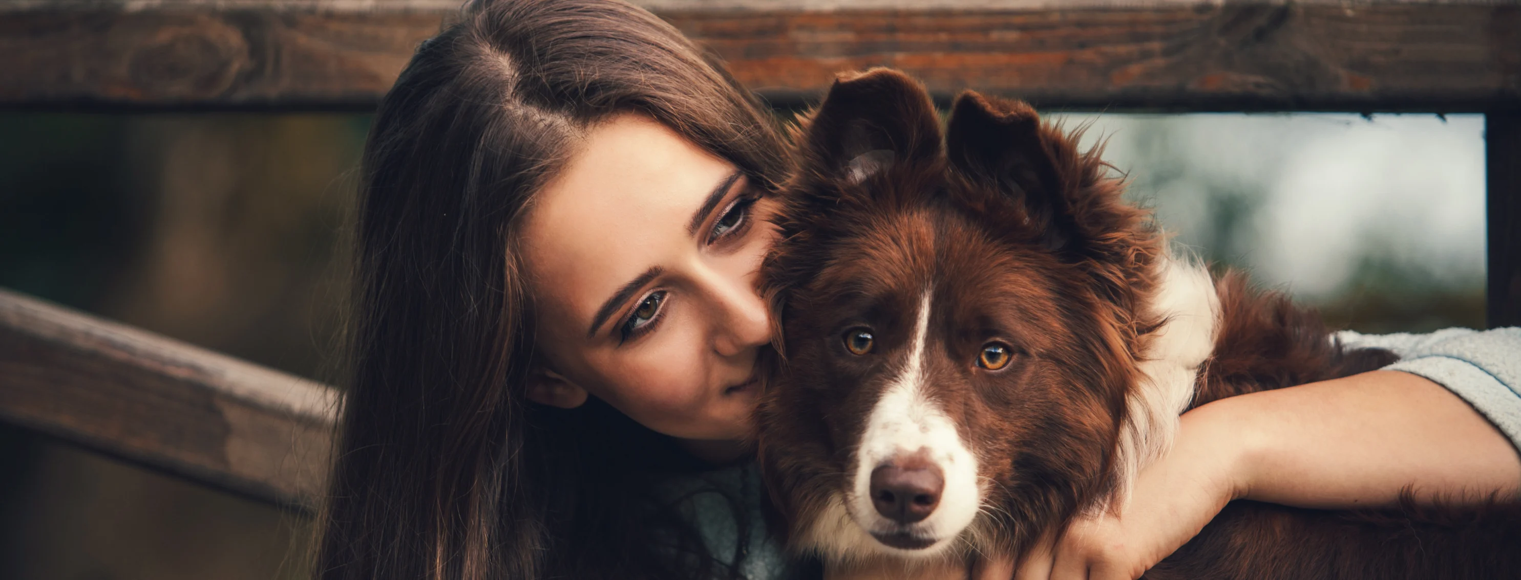 Woman hugging dog in front of gate