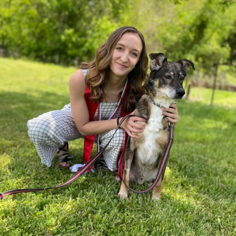 Dr. Brinna Lavelle smiling in the outdoors with a dog. Dr. Brinna Lavelle smiling in the outdoors with a dog.
