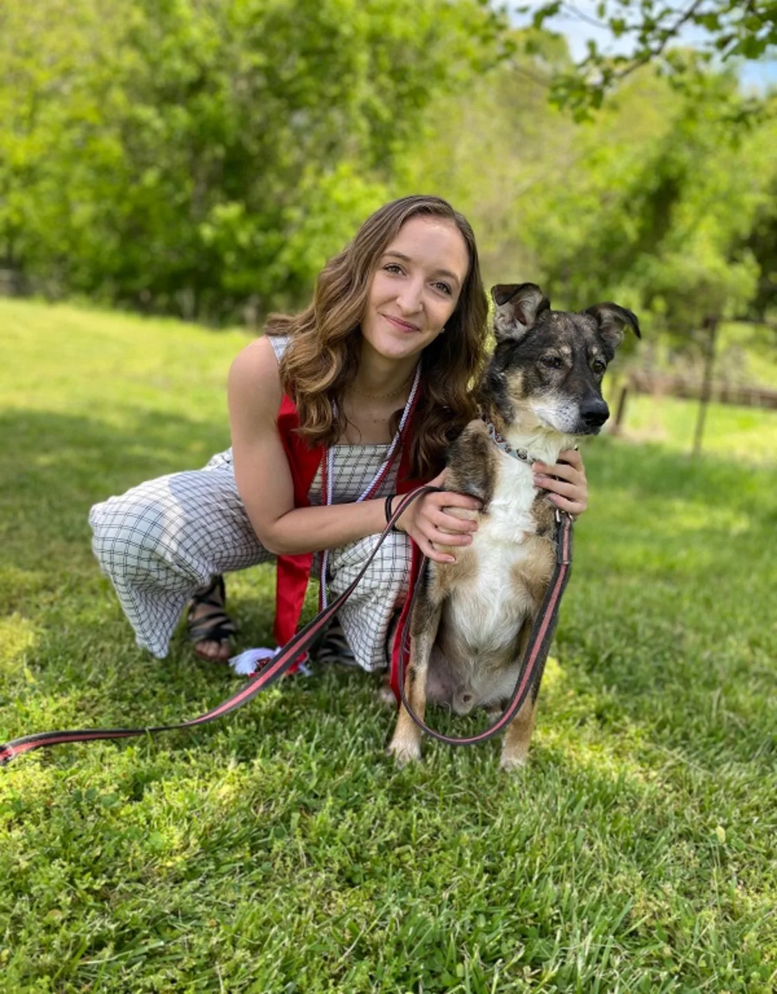 Dr. Brinna Lavelle smiling in the outdoors with a dog. Dr. Brinna Lavelle smiling in the outdoors with a dog.