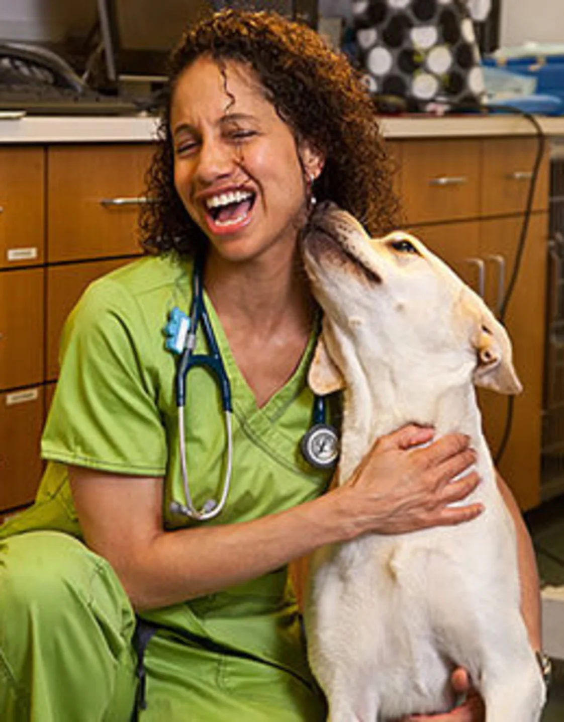 Dr. Adina Mosby kneeling inside while hugging a dog Dr. Adina Mosby kneeling inside while hugging a dog