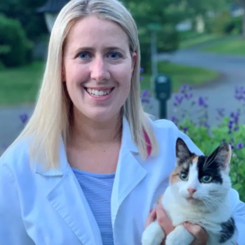 Dr. Bridget Barnes of Northampton Veterinary Clinic standing in front of a pathway, while holding a cat Dr. Bridget Barnes of Northampton Veterinary Clinic standing in front of a pathway, while holding a cat