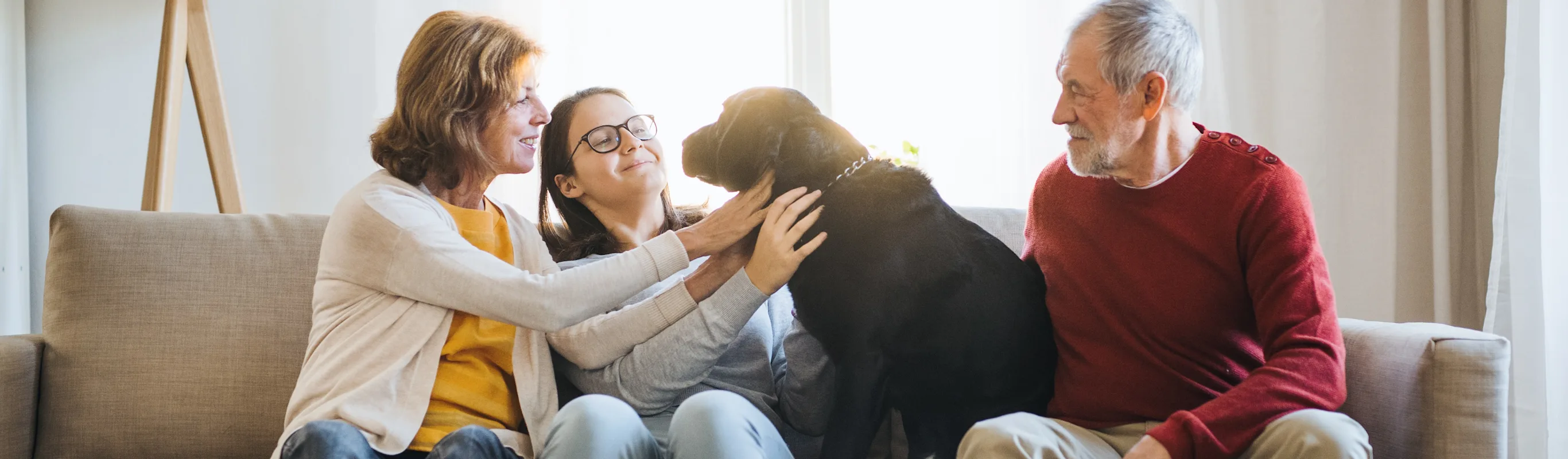 family petting dog on a couch