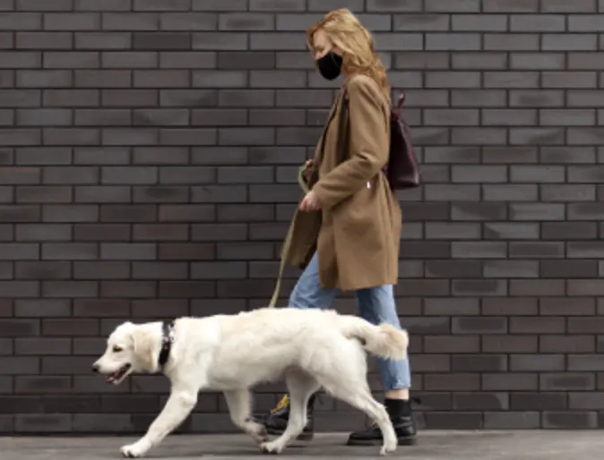 Woman with a face mask on walking her dog