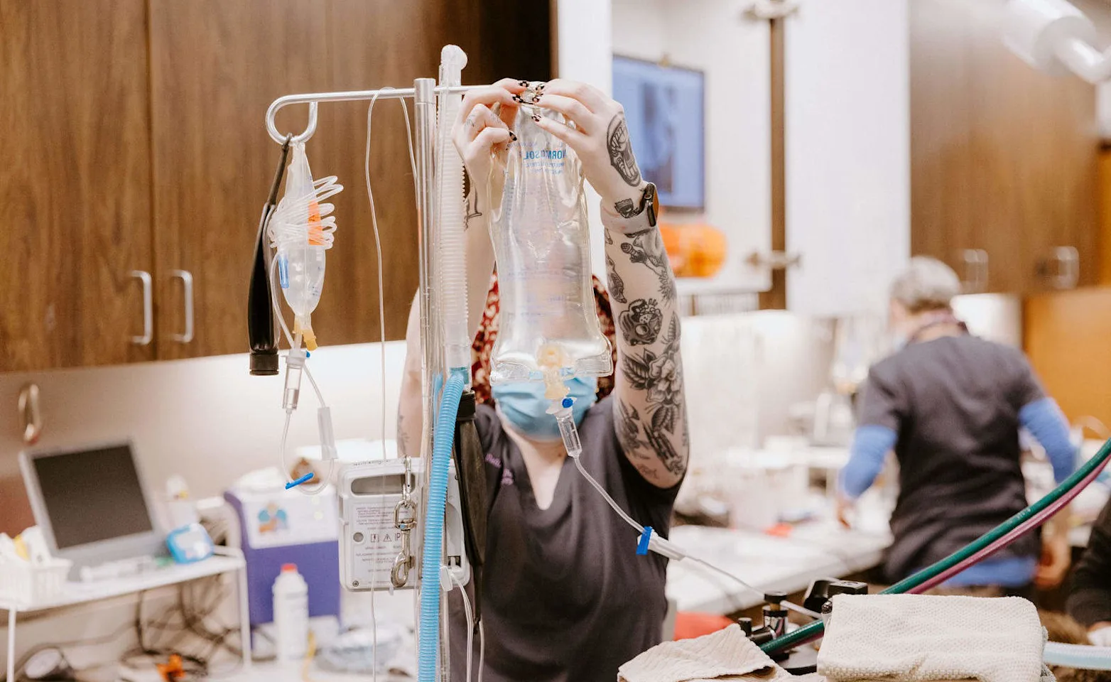 Staff clipping an IV bag to a stand. Staff clipping an IV bag to a stand.